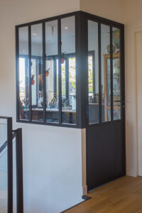 Une pièce avec un escalier métallique et une porte vitrée.