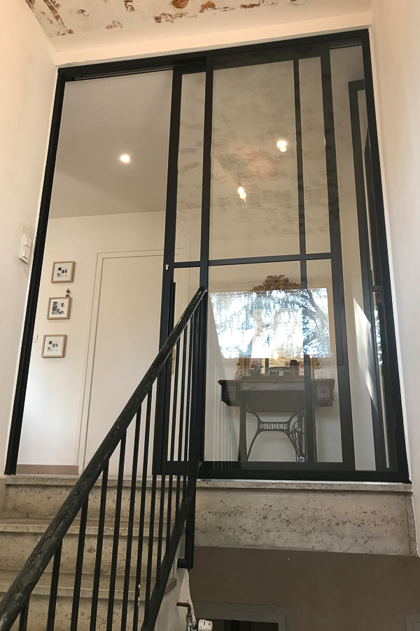Un escalier avec une rampe en métal et une porte vitrée.