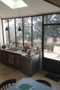Une cuisine avec un grand évier en métal et une fenêtre.