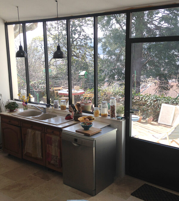 Une cuisine avec un grand évier en métal et une fenêtre.