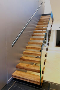 Un escalier en bois avec une rampe en métal et des accents de verre.