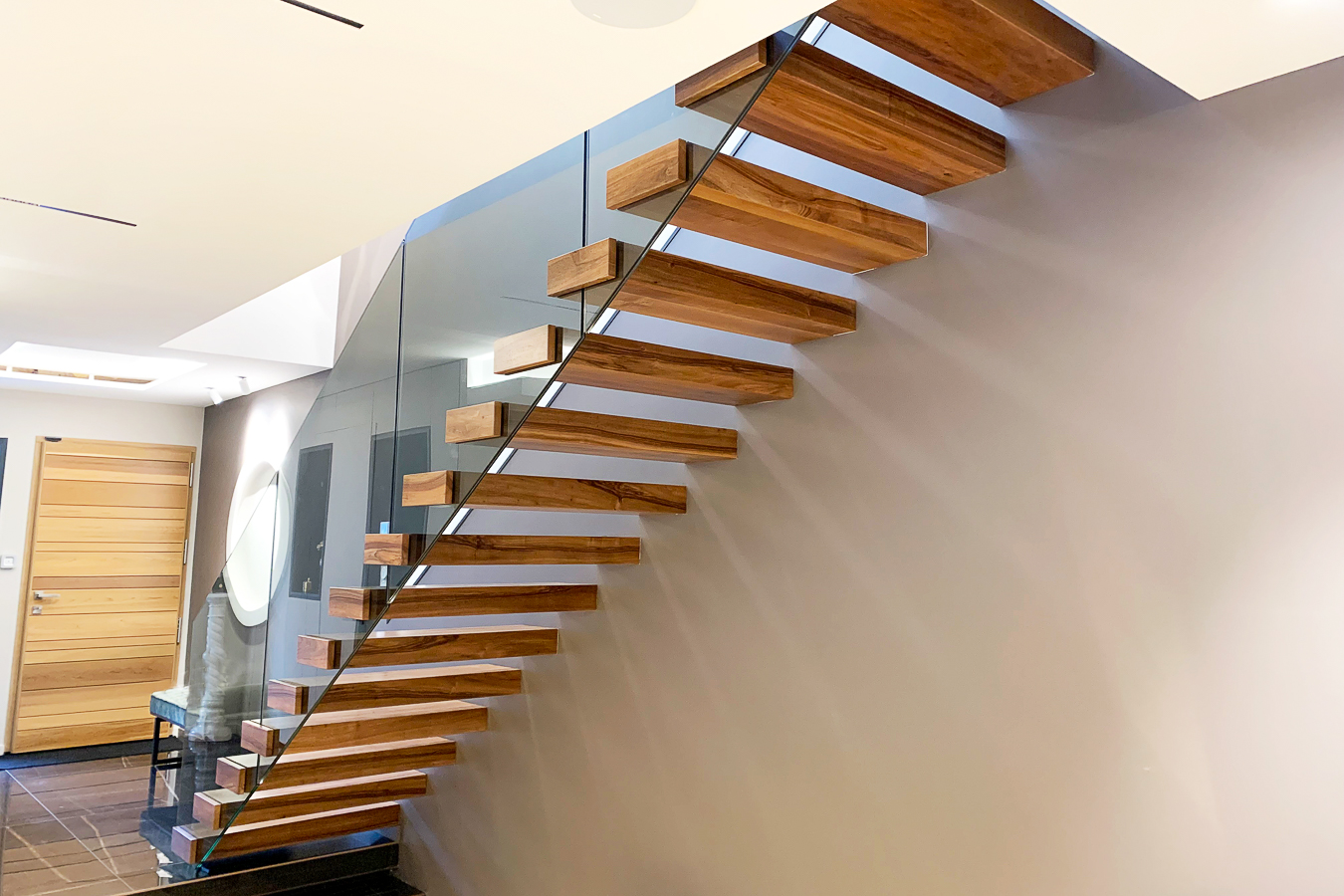 Une maison moderne avec un escalier en bois et des balustrades en verre, avec des accents métalliques.