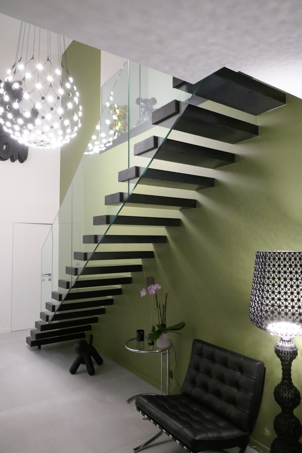 Image d'un escalier métallique sur mesure conçu par un artisan hautement qualifié basé à Lyon, dans le département du Rhône. L'image montre également une lampe noire élégante qui complète le design moderne de la pièce.
