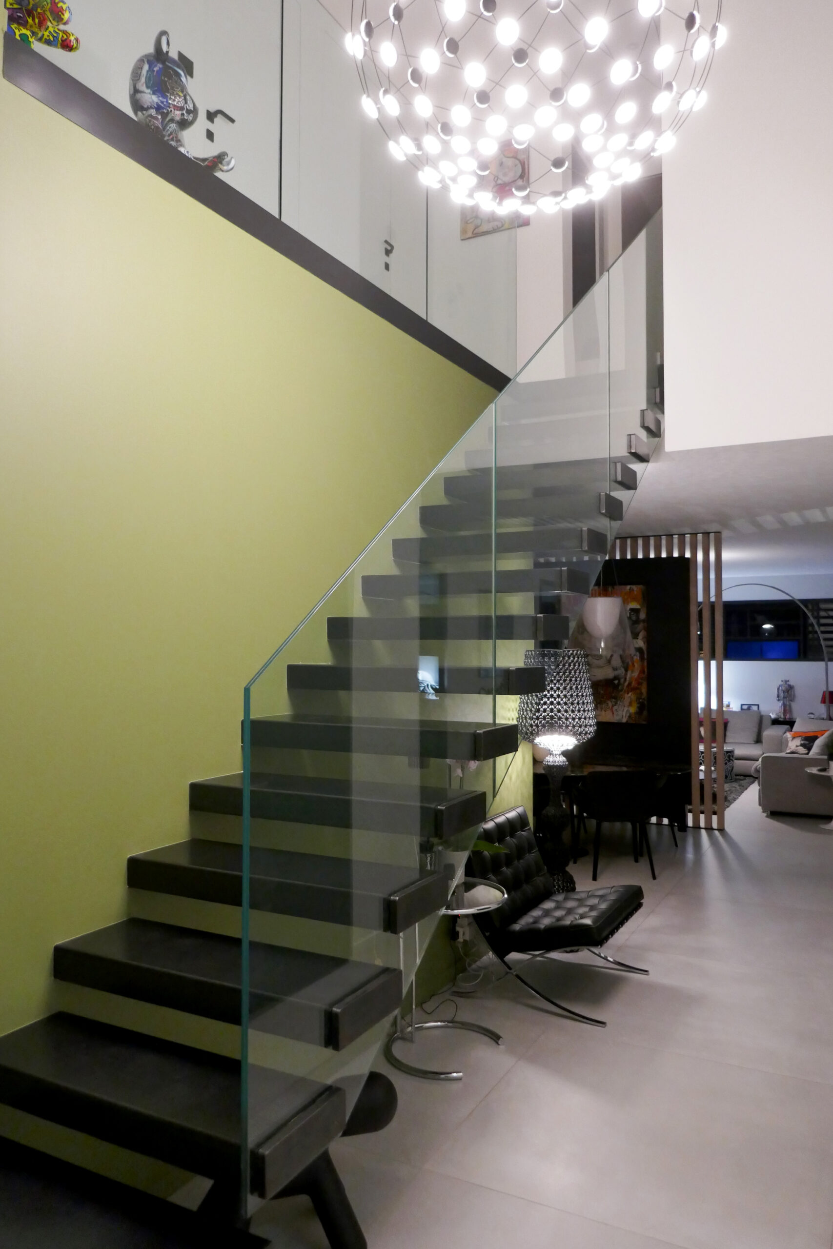 "Superbe escalier métallique sur mesure, doté de marches en verre, créé par un artisan métallier lyonnais dans le département du Rhône, illustrant une réalisation haut de gamme installée dans un salon."
