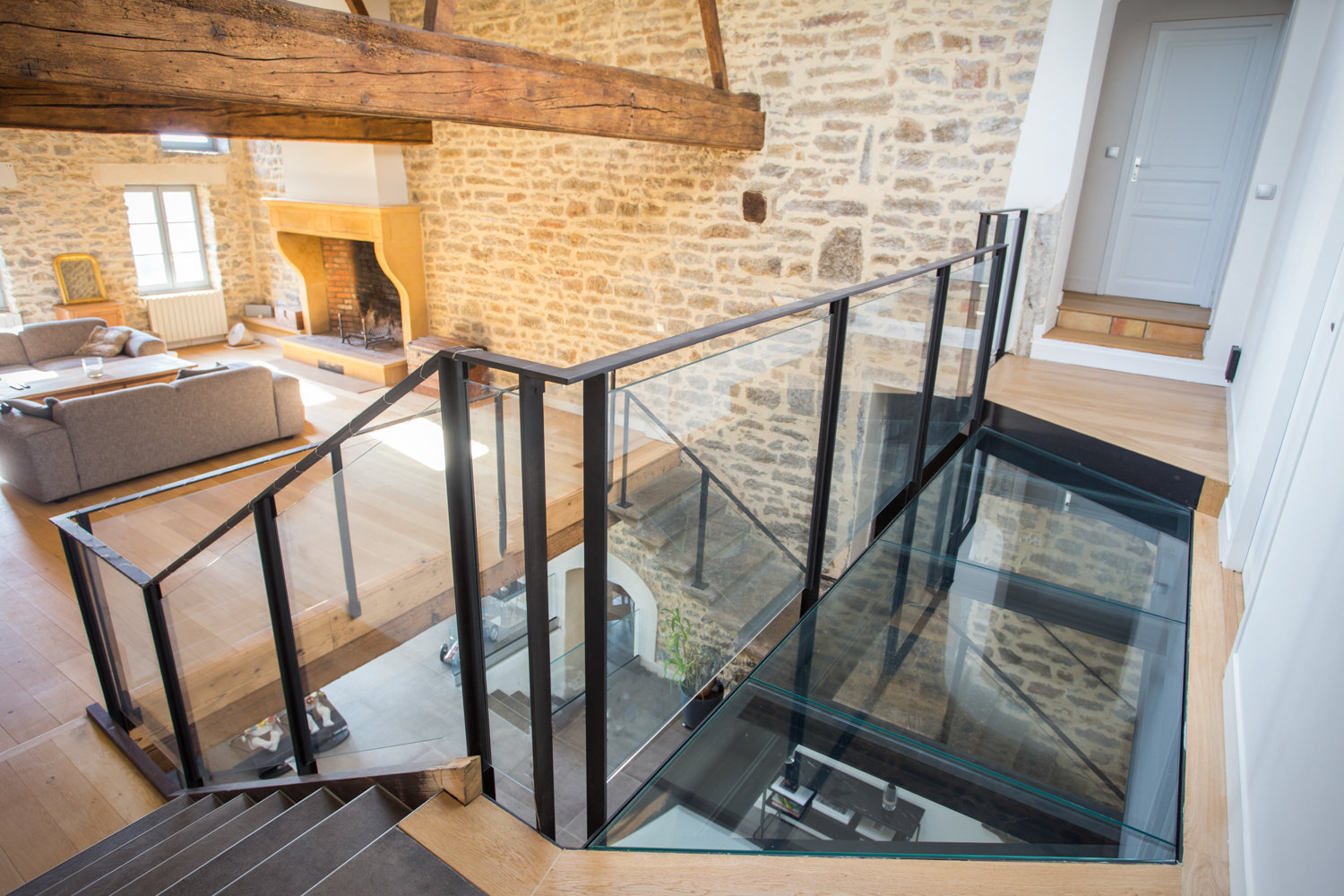 Un escalier en verre dans une maison aux murs en pierre.