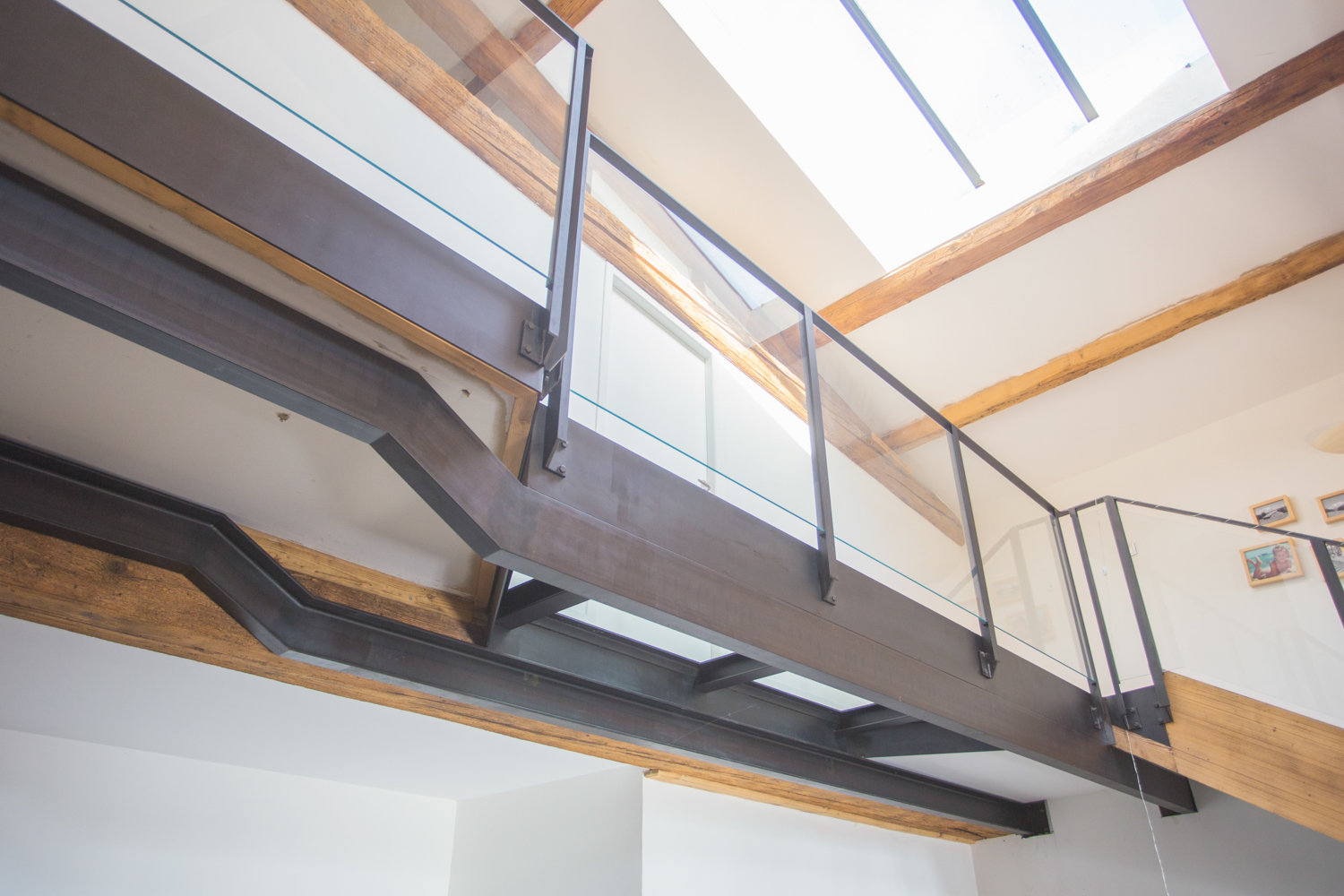 Un escalier avec garde-corps métallique et puits de lumière.
