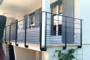 Un balcon avec une balustrade et des volets noirs.