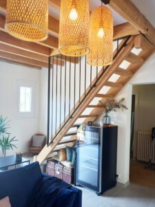 Un salon avec un escalier en bois et un canapé bleu.