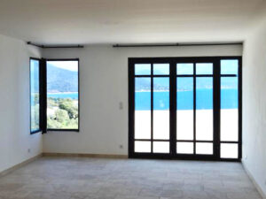 Une pièce vide avec des portes coulissantes en verre et une vue sur l'océan.