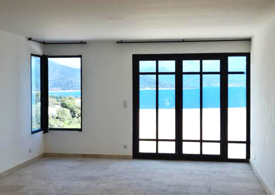 Une pièce vide avec des portes coulissantes en verre et une vue sur l'océan.
