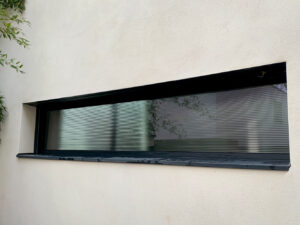 Une fenêtre avec un cadre noir sur un mur blanc.