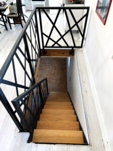 Un escalier avec une rampe en métal et du parquet.