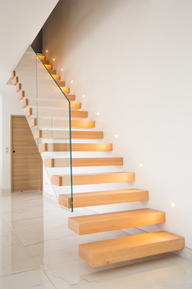 Escalier intérieur suspendu en bois et rambarde en verre.