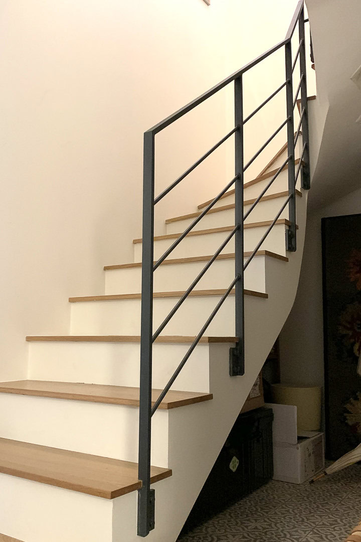 Escalier en bois avec contremarches blanches et rampes dans un intérieur moderne.