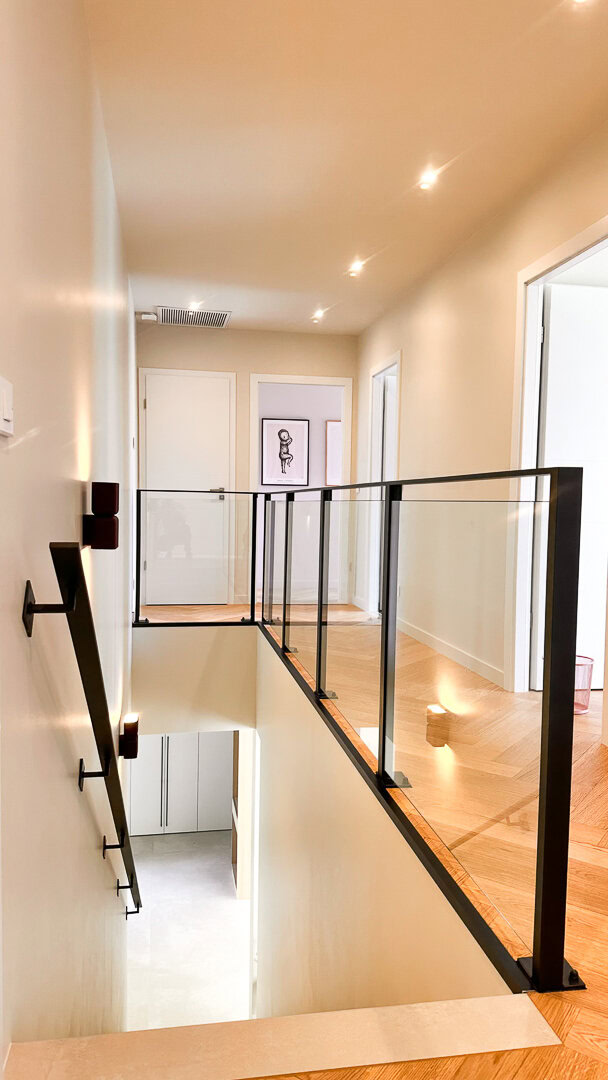 Une rampe en métal et en verre borde un escalier, mettant en valeur le savoir-faire d'une entreprise de métallerie basée dans le Rhône, près de Lyon.