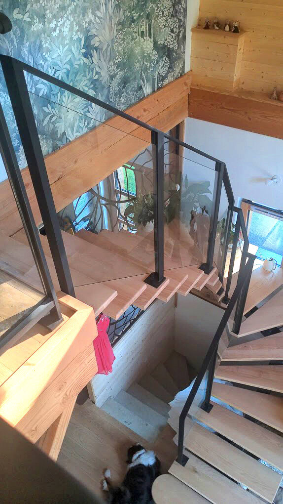 Escalier en métal avec garde-corps noir et panneaux de verre, conçu et installé par un métallier du Rhône près de Lyon.
