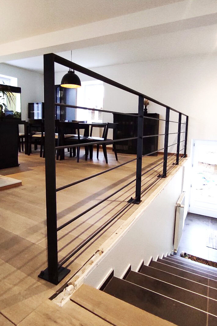 Une rampe moderne en métal noir, conçue et installée par un métallier de la région lyonnaise, met en valeur l'escalier.