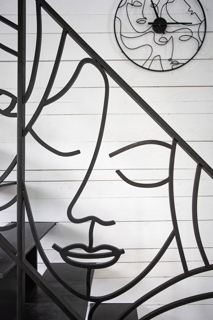 Une rampe d'escalier en métal avec un motif de visage abstrait, illustrant le travail créatif du métal d'un artisan près de Lyon.