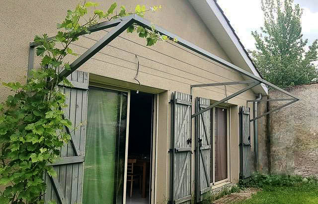 Armature métallique d'un store de terrasse conçu et posé par un métallier, apposé au-dessus des portes d'une maison près de Lyon.