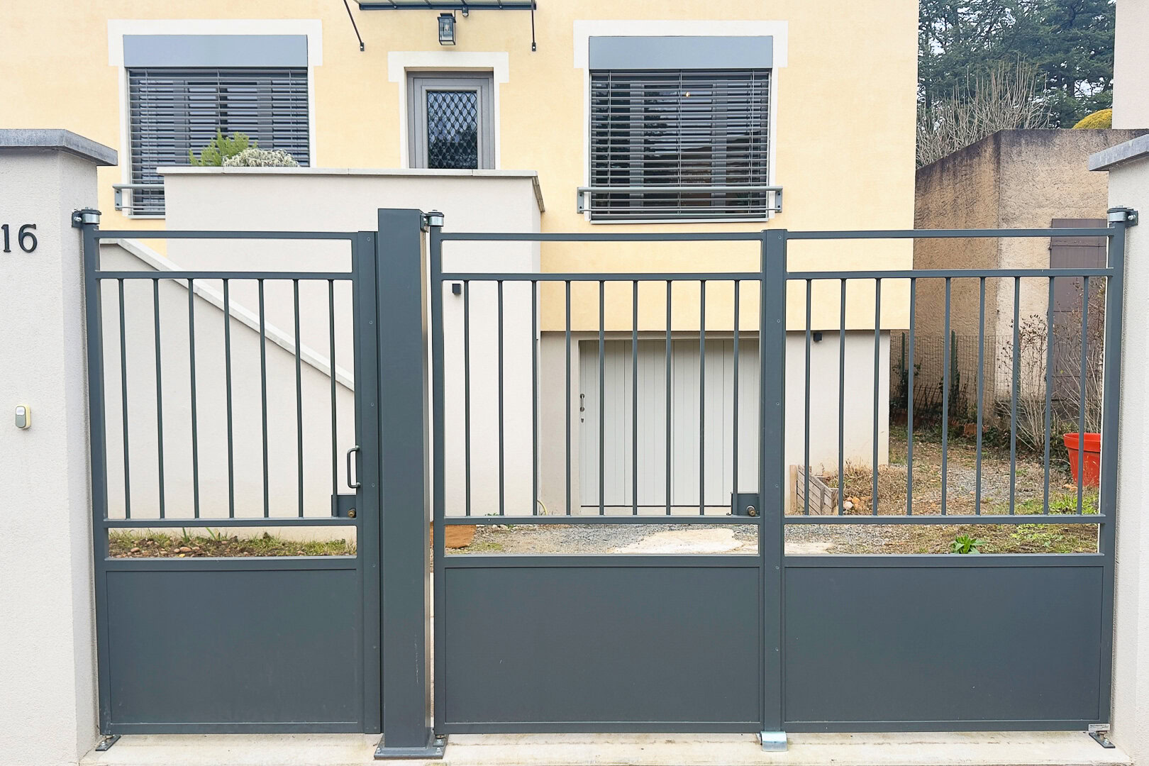 Portail moderne en métal gris à barreaux verticaux, mettant en valeur le savoir-faire d'un métallier près de Lyon, dans le Rhône.