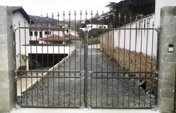 Portail en métal orné de pointes décoratives, réalisé par un métallier basé dans le Rhône, installé à l'entrée d'une propriété.