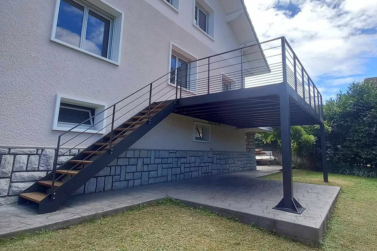 Escalier en métal avec garde-corps menant à une terrasse métallique, réalisés par un métallier près de Lyon.