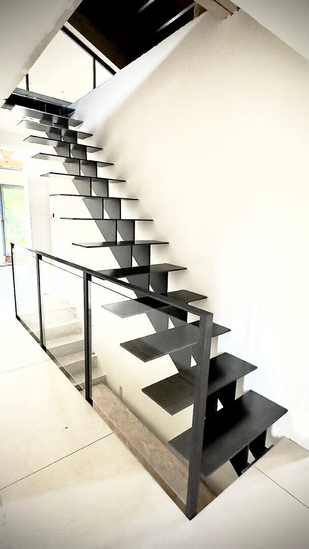 Escalier flottant moderne en métal noir avec contremarches ouvertes, conçu, fabriqué et installé par un métallier du Rhône.