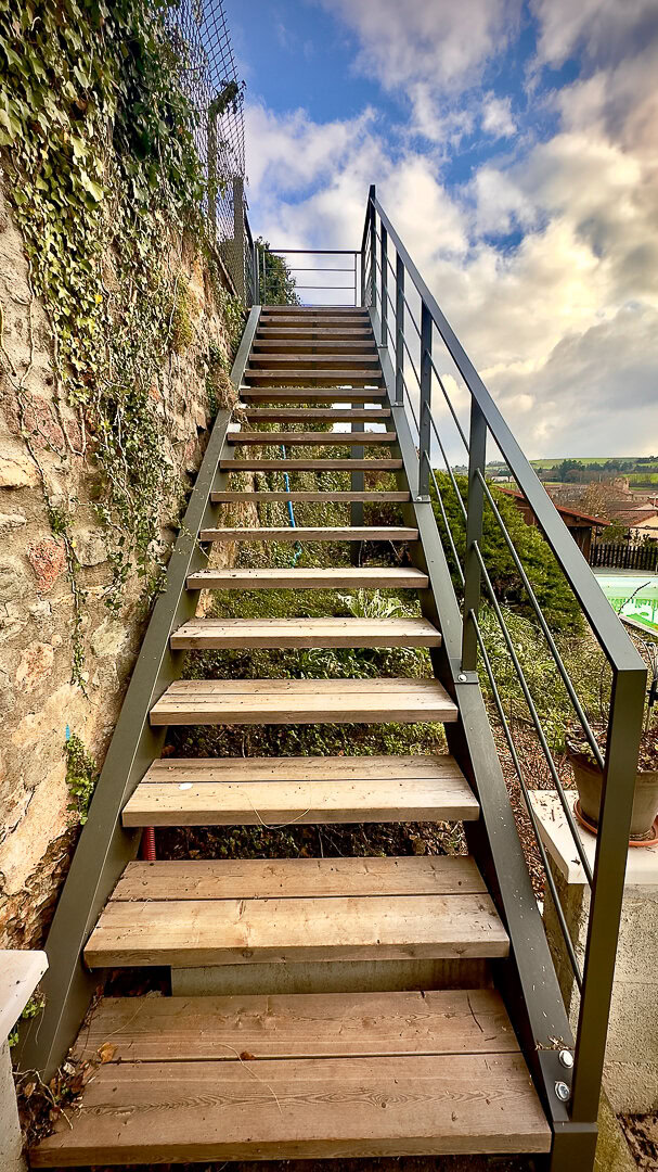 Des rampes métalliques fabriquées par un métallier du Rhône bordent un escalier, mettant en valeur la précision du design et l'expertise de la fabrication métallique.