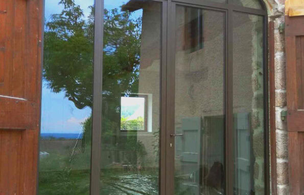 Verrière cintrée réalisée sur mesure, intégrée dans une arche en pierre.